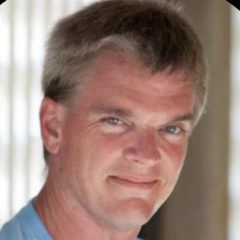 Smiling white man headshot wearing a blue shirt